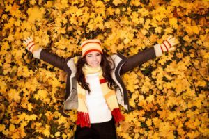 16861010 - autumn woman lying over leaves and smiling, top view